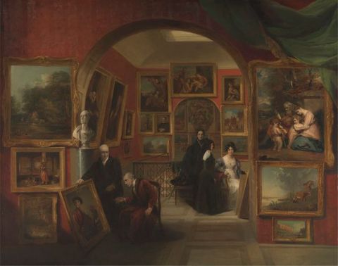 Painting. A room opens onto two further rooms, each separated by an arch. The rooms all have red walls are densely decorated with paintings. Two pale-skinned men in the room nearest us hold and examine a painting that is propped up on the wall. In the second room, three pale-skinned women are also looking at a painting propped up against the wall, its back towards us.